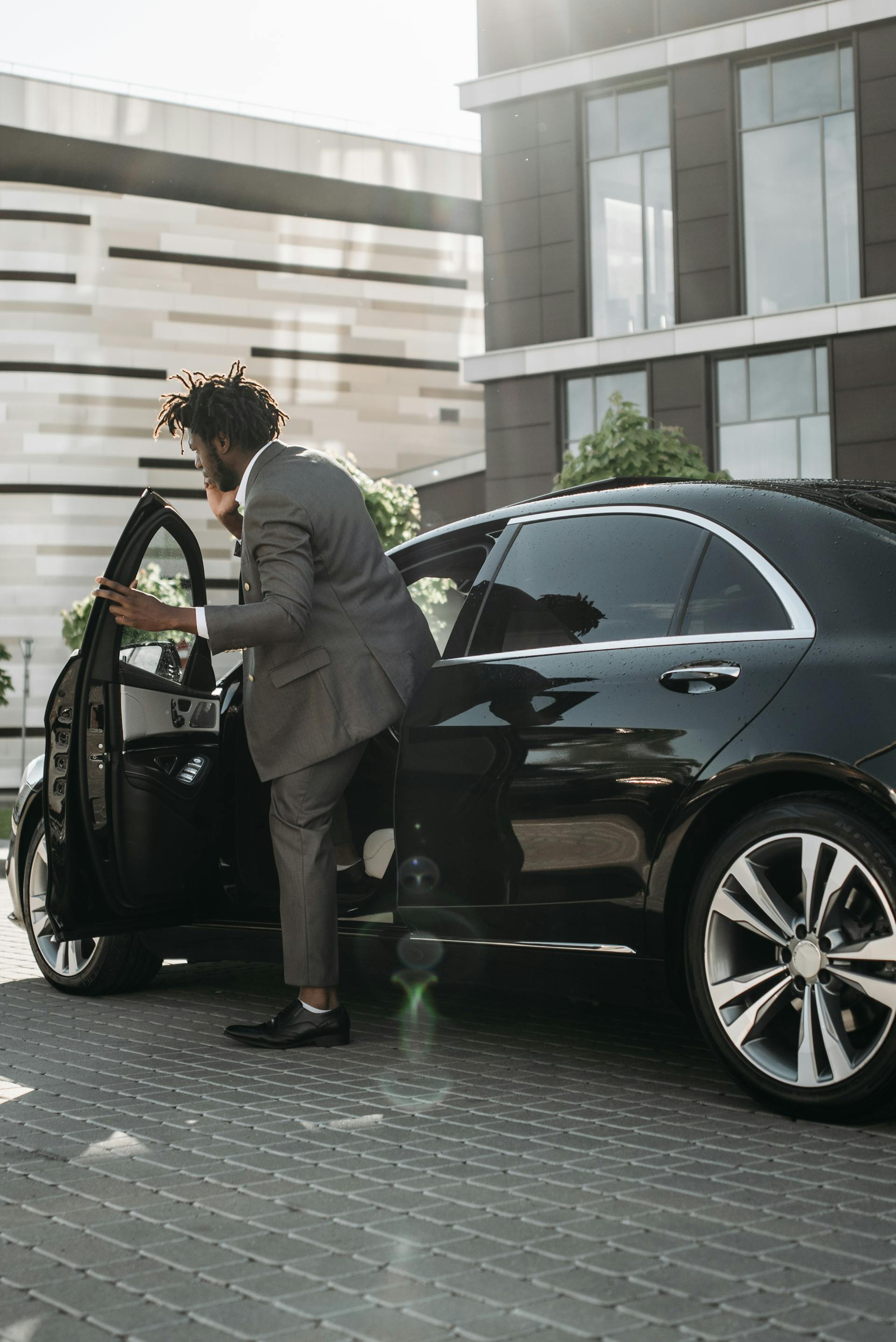 Professional chauffeur in suit beside black luxury SUV